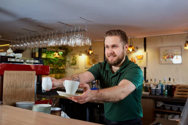 Barista con taza de café en la mano detrás de la barra . — Foto de Stock