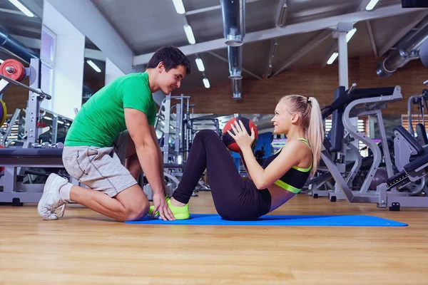 Yerdeki bir eğitmen adamla ABS egzersizleri yapıyor spor kız bir — Stok fotoğraf