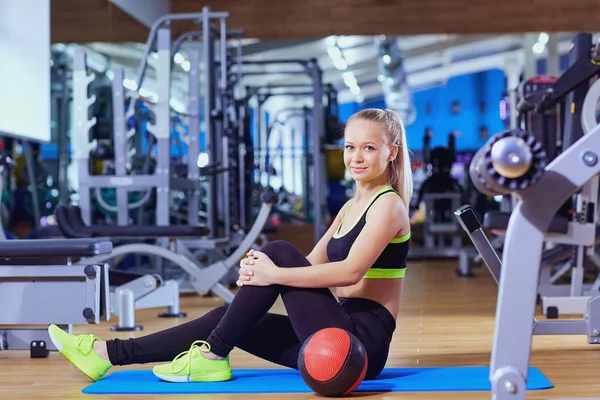 Hermosa chica rubia en ropa deportiva en el suelo con gimnasio de pelota — Foto de Stock