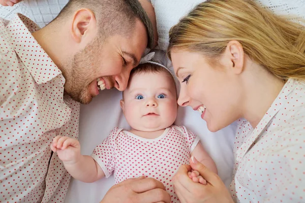 Familia feliz. Madre y padre están acostados en la cama con su — Foto de Stock