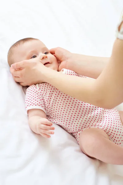 Les mains des mamans tiennent leur bébé sur un lit blanc — Photo