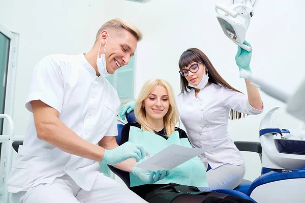 De patiënt, de tandarts en de assistent in het kantoor van een tandheelkundige kliniek — Stockfoto