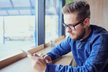 Tablet elinde serbest hipster adamla Cafe tarafından t çalışır.