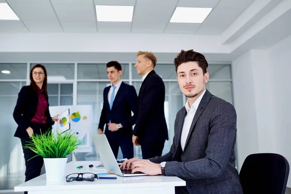 Jovem com um laptop à mesa no escritório moderno — Fotografia de Stock