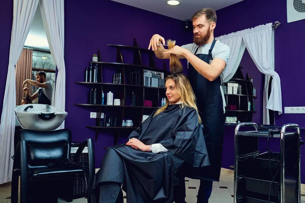 Мужчина парикмахер стрижется для женщины в салоне красоты для волос — стоковое фото