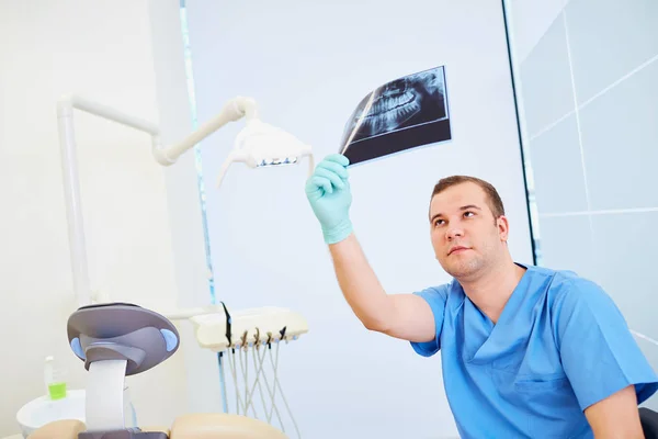 Человек-дантист смотрит на рентген в стоматологическом кабинете — стоковое фото
