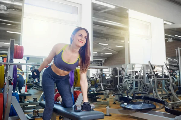 Joven chica deportiva con mancuernas en las manos haciendo ejercicios en spo — Foto de Stock