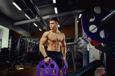 İçinde karanlık bir jimnastik salonu kas adam. Bir sporcunun dumbbel ile eğitim