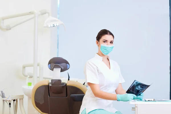 A dentist woman looks at an x-ray  workplace in  dental office — Stock Photo, Image
