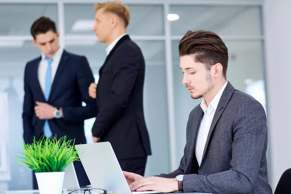 Biznesmen na jego biurku w pracy na laptopie w tle bu — Zdjęcie stockowe