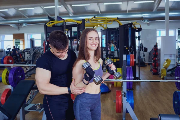 Entrenador personal ayuda a chica deportiva haciendo ejercicios con mancuerna — Foto de Stock