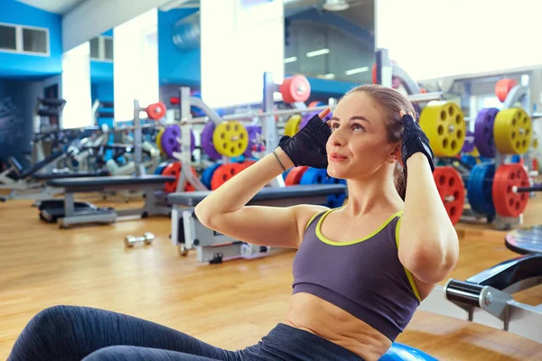 Deportiva chica está haciendo abdominales ejercicio en el suelo en el gimnasio — Foto de Stock