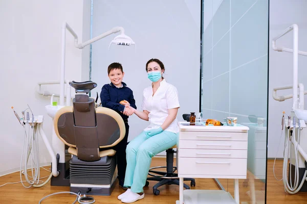 Doktor diş hekimi ve çocuk el sıkışma ofiste. Diş treatme — Stok fotoğraf
