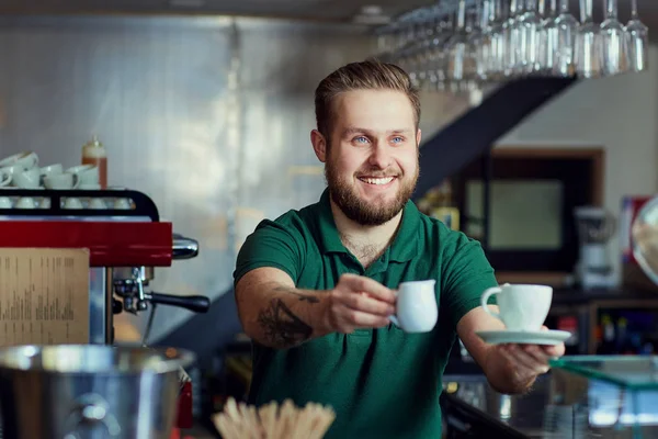 Barista con taza de café en la mano detrás de la barra. Cafetería de bienvenida — Foto de Stock