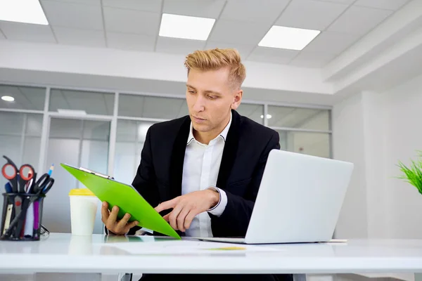 Empresário loira trabalhando em um laptop sua mesa no escritório — Fotografia de Stock