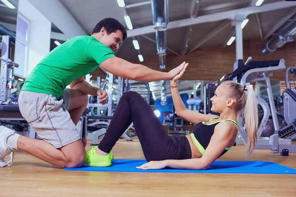 Yerdeki bir eğitmen adamla ABS egzersizleri yapıyor spor kız bir — Stok fotoğraf