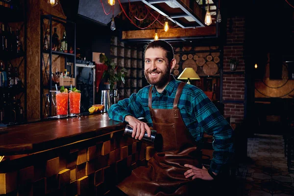 Портрет бармена-хипстера с бородой, улыбающегося сидя в баре — стоковое фото