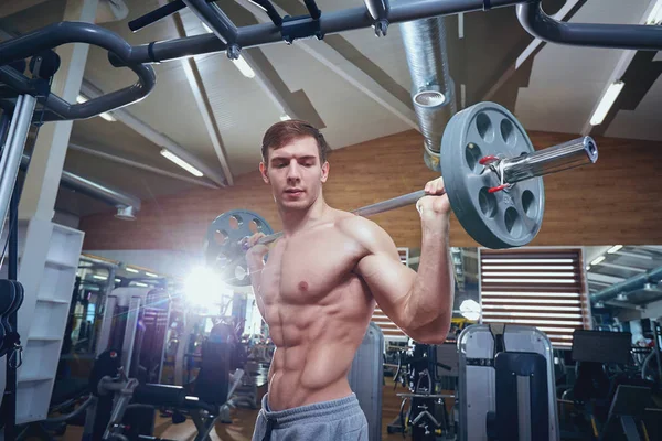Atlet laki-laki melakukan latihan dengan sebuah bar tergeletak di gym — Stok Foto