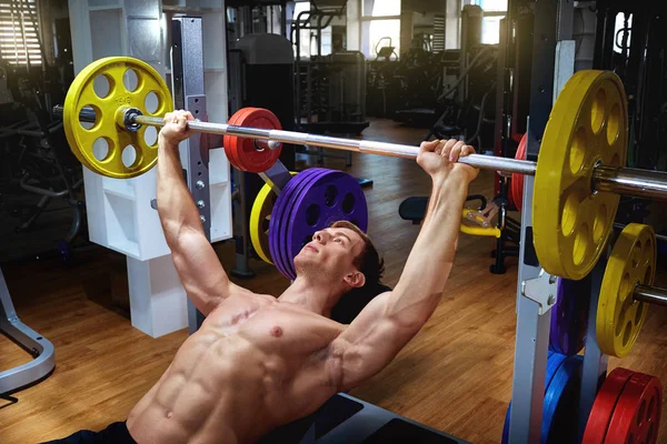 Atlet laki-laki melakukan latihan dengan sebuah bar tergeletak di gym — Stok Foto