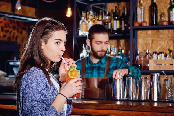 Chica bebe un cóctel de paja en el bar sobre fondo barmans —  Fotos de Stock