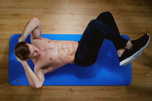 Visão superior de um cara masculino desportivo fazendo exercícios abdominais no chão em th — Fotografia de Stock