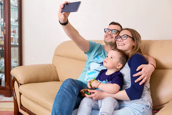 Μητέρα, πατέρας και γιος χαμόγελο, κάνει selfie στο τηλέφωνο κάθεται στο — Φωτογραφία Αρχείου