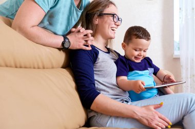 Mutlu bir aile ile bir tablet kanepede odasında oturuyor