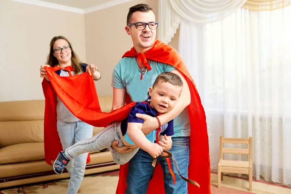 Uma família vestida com fantasias de super-herói joga o quarto — Fotografia de Stock