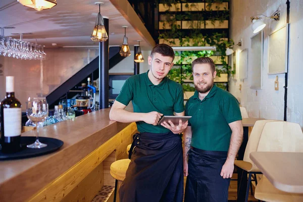 Two bartenders waiter with a gadget tablet in  bar — Stock Photo, Image