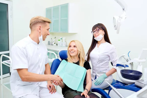 O dentista aperta as mãos com o paciente após o tratamento dentário — Fotografia de Stock