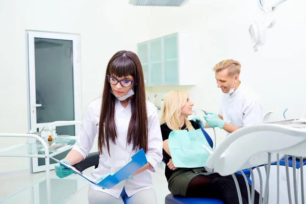 Dentiste femme dans des lunettes avec un dossier mains sur fond équiper — Photo