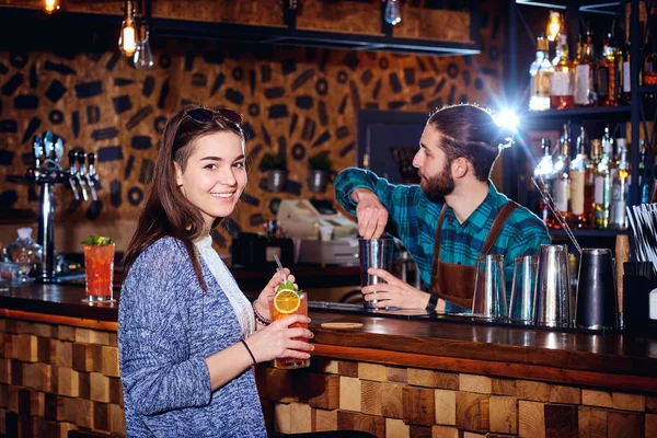 Une fille avec un cocktail sourit derrière le comptoir au bar — Photo