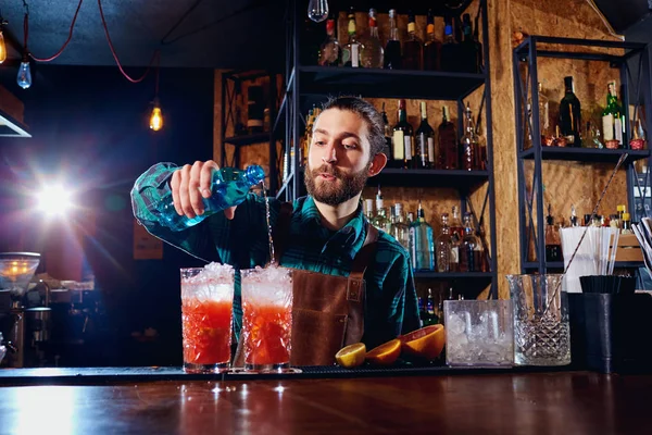 Bartender hipster with a beard makes an alcoholic cocktail behi — Stock Photo, Image