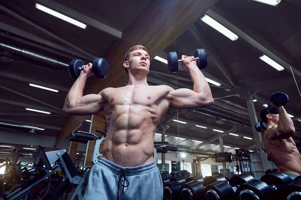Pria dengan tokoh olahraga dengan dumbbells di gym — Stok Foto