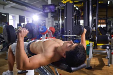 Bir adam yapıyor yalan dumbbells ile spor salonunda egzersiz