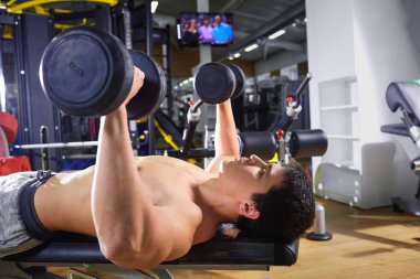 Bir adam yapıyor yalan dumbbells ile spor salonunda egzersiz