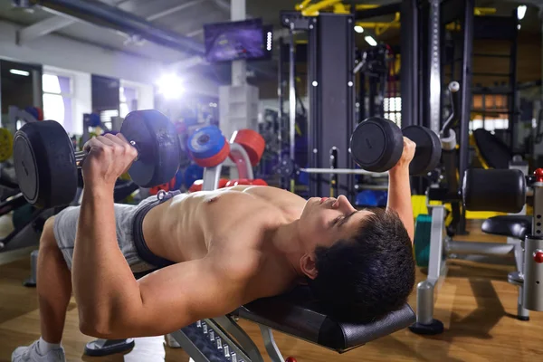 Seorang pria dengan dumbel berbohong melakukan latihan di gym — Stok Foto