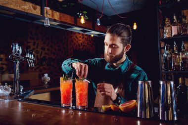 Barmen sakallı bir kokteyl tezgahın arkasındaki ba yapar.