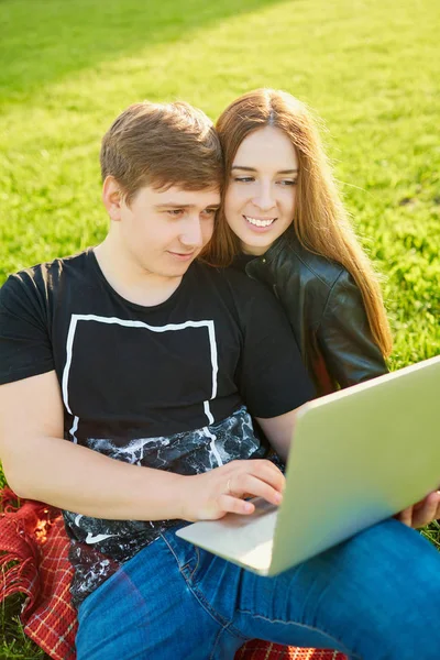 Loving para z laptopa w parku o zachodzie słońca — Zdjęcie stockowe