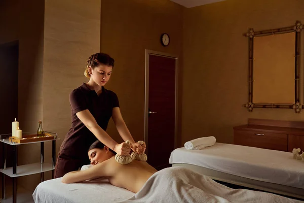 Sacs de massage pour le corps sur le dos d'une fille dans un salon de beauté spa — Photo