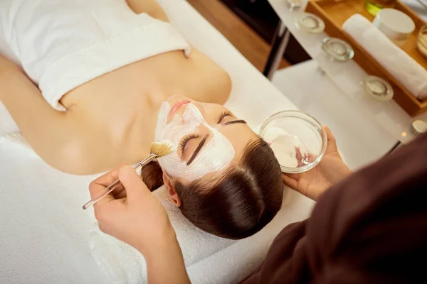 Güzellik uzmanı bir maske krem spa s kız yüzüne koyar — Stok fotoğraf