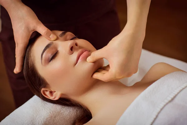 Krásná žena je dána obličeje masáž v lázeňském salonu — Stock fotografie