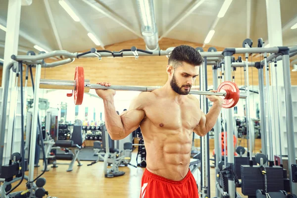 Culturista con una barra de barra hace ejercicios en el gimnasio —  Fotos de Stock