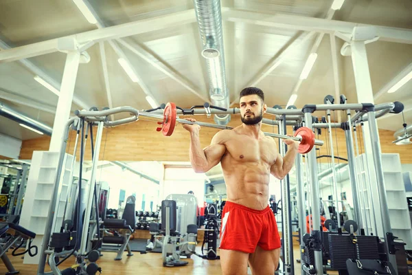 Vücut geliştiricisi olan çubuk halter egzersiz spor salonunda yapar — Stok fotoğraf
