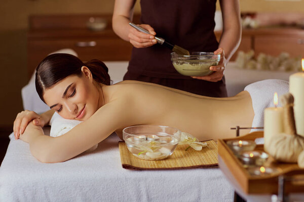 Young woman is put on a mask on her back in  spa salon