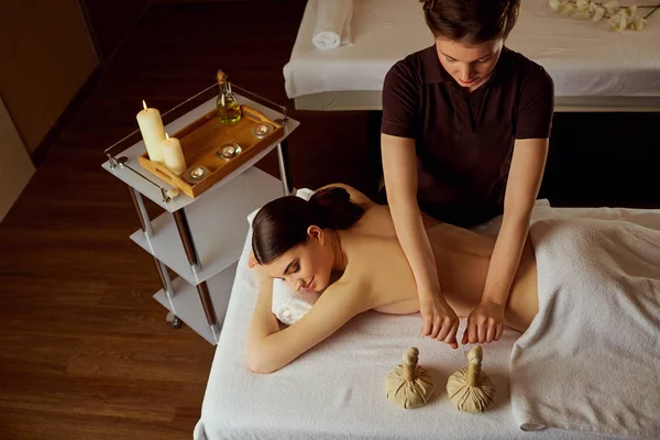 Massage of young woman lying in spa salon