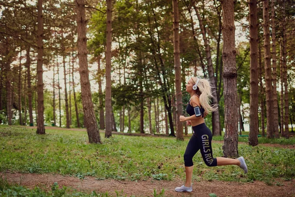 Дівчина в навушниках біжить лісом — стокове фото