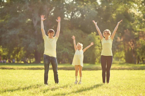 Boldog család parkban kezeket fel. — Stock Fotó