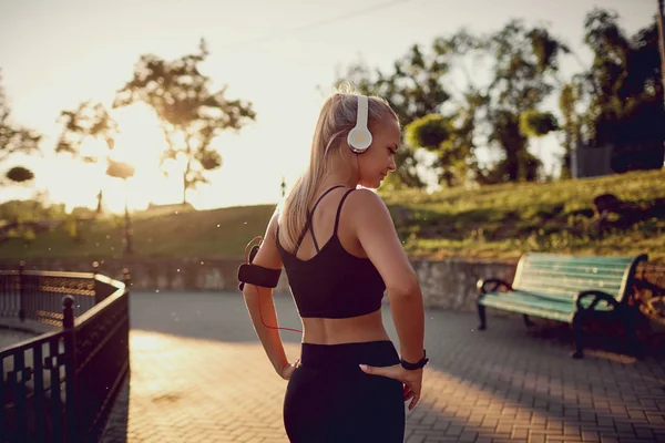 Ragazza in cuffia su una corsa al parco al tramonto . — Foto Stock