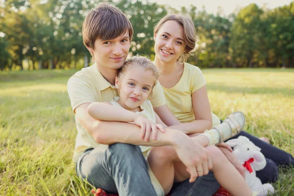 Retrato de una familia sentada en el parque sobre la hierba — Foto de Stock